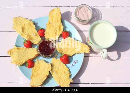 Délicieux petit déjeuner avec croissants frais, fraises, lait et yaourt sur vieux fond de bois, Banque D'Images