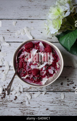 Chia noix de coco avec sauce aux framboises pouding, flocons de noix de coco et du cacao nibs dans un bol Banque D'Images