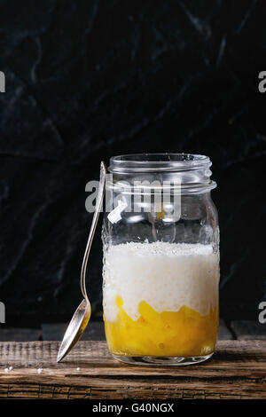 Des perles de tapioca au lait dessert avec du lait de coco et mangue. Servi dans un bocal en verre sur la planche à hacher plus vieux vintage woode Banque D'Images