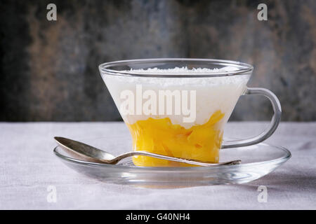 Des perles de tapioca au lait dessert avec du lait de coco et mangue. Servi en verre sur une soucoupe sur nappe blanche avec de vieux gra Banque D'Images