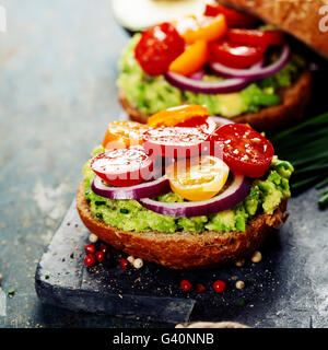 De savoureux sandwiches faits maison avec de l'avocat, la tomate, l'oignon et le poivre sur une liste de sélection Banque D'Images