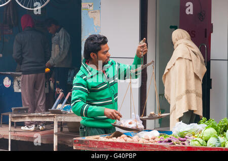 Vendeur Indien non identifiés avec des poids sur la rue à Varanasi. L'Uttar Pradesh, Inde Banque D'Images