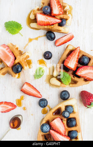 Gaufres Belges faites maison servi sur un plateau avec woodenl blanc , petits fruits et feuilles de menthe sirop marple, vue du dessus Banque D'Images