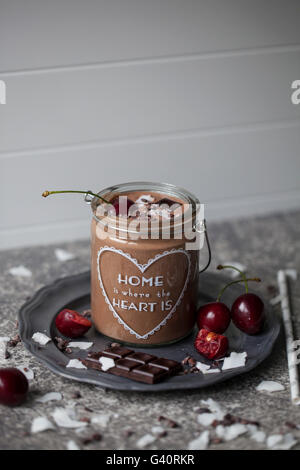 Smoothie au chocolat et à la noix de coco dans un pot garni de cerise, de chocolat noir, de flocons de noix de coco et du cacao nibs Banque D'Images