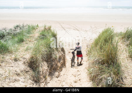 Randonnée à vélo le long d'une partie de 8kms de long vide Pembrey Sands Beach sur un dimanche ensoleillé de juin. Carmarthenshire, Pays de Galles Banque D'Images