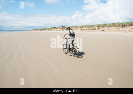 Randonnée à vélo le long d'une partie de 8kms de long vide Pembrey Sands Beach sur un dimanche ensoleillé de juin. Carmarthenshire, Pays de Galles Banque D'Images