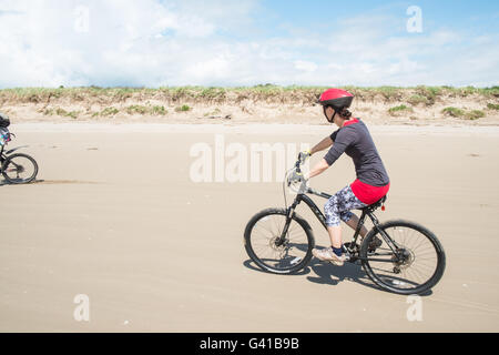 Randonnée à vélo le long d'une partie de 8kms de long vide Pembrey Sands Beach sur un dimanche ensoleillé de juin. Carmarthenshire, Pays de Galles Banque D'Images