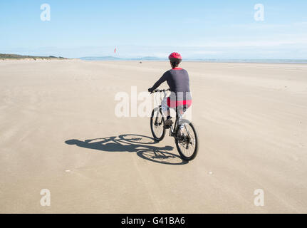 Randonnée à vélo le long d'une partie de 8kms de long vide Pembrey Sands Beach sur un dimanche ensoleillé de juin. Carmarthenshire, Pays de Galles Banque D'Images