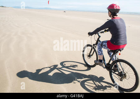 Randonnée à vélo le long d'une partie de 8kms de long vide Pembrey Sands Beach sur un dimanche ensoleillé de juin. Carmarthenshire, Pays de Galles Banque D'Images