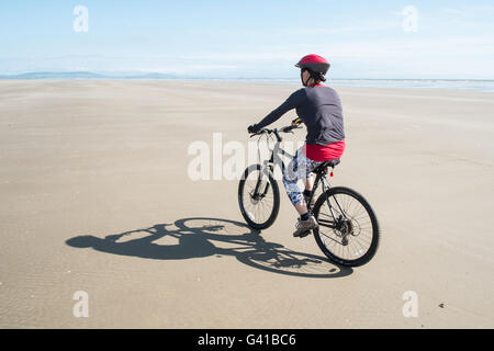 Randonnée à vélo le long d'une partie de 8kms de long vide Pembrey Sands Beach sur un dimanche ensoleillé de juin. Carmarthenshire, Pays de Galles Banque D'Images