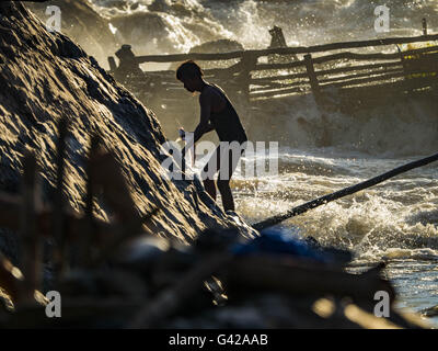 Don Khone, Champassak, le Laos. 18 Juin, 2016. Un pêcheur avec ses prises grimpe les rochers sur le rivage à Khon Pa Soi Cascades, sur le côté est de Don Khon. C'est le plus petit des deux chutes d'eau en Don Khon. Les pêcheurs ont construit un système complexe de ponts de cordes au-dessus des chutes qu'ils utilisent pour se rendre à l'pièges à poissons. Les pêcheurs de la région sont aux prises avec une baisse des rendements et les petits poissons, qui menaçaient leur mode de vie. Le Mékong est l'un des plus riches et productifs fleuves sur Terre. C'est un haut lieu mondial pour les poissons d'eau douce : plus de 1 000 espèces ont été enregistrées le Banque D'Images