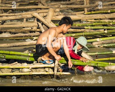 Don Khone, Champassak, le Laos. 18 Juin, 2016. Les pêcheurs travaillent sur leurs pièges à poissons à Khon Pa Soi Cascades, sur le côté est de Don Khon. C'est le plus petit des deux chutes d'eau en Don Khon. Les pêcheurs ont construit un système complexe de ponts de cordes au-dessus des chutes qu'ils utilisent pour se rendre à l'pièges à poissons. Les pêcheurs de la région sont aux prises avec une baisse des rendements et les petits poissons, qui menaçaient leur mode de vie. Le Mékong est l'un des plus riches et productifs fleuves sur Terre. C'est un haut lieu mondial pour les poissons d'eau douce : plus de 1 000 espèces ont été enregistrées il y a, en second lieu seulement à Banque D'Images