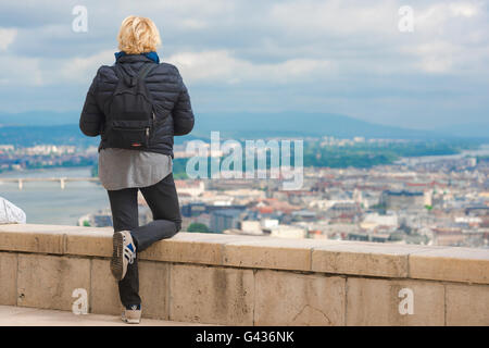 Une jeune femme portant un sac à dos de touriste les enquêtes centre de Budapest à partir du sommet du mont Gellért-hegy (Hill) sur le côté Buda du Danube, en Hongrie. Banque D'Images