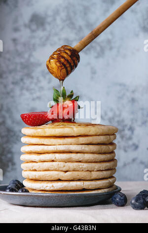 Crêpes de fraises et de bleuets en bleu plaque en céramique, et d'écoulement de miel Miel de bois, servi sur balancier wh Banque D'Images