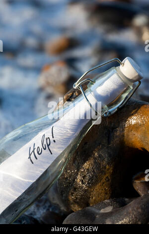 Un message d 'Aide' dans une bouteille en verre sur une plage Banque D'Images