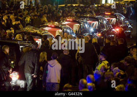 Les gens placent des fleurs sur la corée transportant le Soldat Conrad Lewis comme cortège contenant le drapeau de l'Union des cercueils drapés de cinq militaires de l'armée britannique, qui tous sont morts dans une semaine l'un de l'autre, Pauses sur High Street dans la ville de Wootton Bassett, dans le Wiltshire, en route vers l'hôpital John Radcliffe, Oxfordshire, en tant que famille et amis du Soldat Conrad Lewis, du Soldat Robert Wood, du Soldat Dean Hutchinson, du Soldat Lewis Hendry et du Caporal de lance Kyle Marshall, Sont rejoints par le peuple de Wootton Bassett pour rendre hommage aux hommes tombés. Banque D'Images