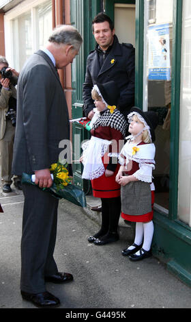 Le prince de Galles reçoit un don de jonquilles de Teah Ross (à gauche), 6 ans, et de sa sœur Amelia, 4 ans, lors de sa visite d'une journée à St David dans la ville de Llandovery, dans le sud du pays de Galles. Banque D'Images