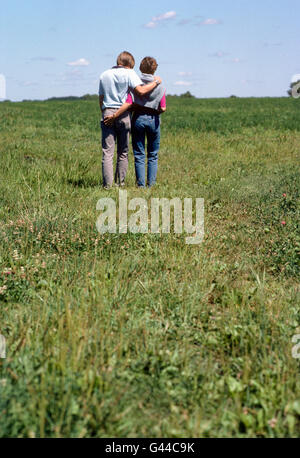 Jeune couple marchant sur terrain couvert d'herbe Banque D'Images