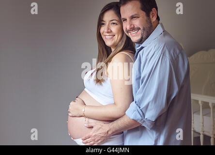 Mari serrant sa femme enceinte, de la chambre de bébé. Banque D'Images