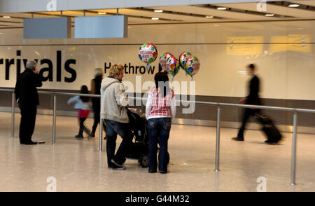 Une famille apporte des ballons de bienvenue à la maison pour rencontrer ses proches au terminal 5 de l'aéroport d'Heathrow, alors que les passagers arrivent au Royaume-Uni. Banque D'Images