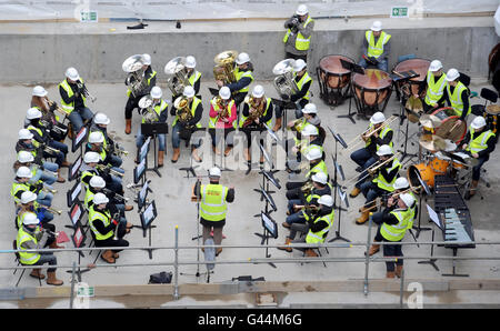 Plus de 40 musiciens de cuivres et de percussions de la Guildhall School of Music and Drama exécutent un « bal de chapeau » sur le plancher de la nouvelle salle de concert de l'école qui est actuellement en cours de développement à Milton court à Londres. Banque D'Images