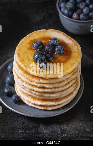 Crêpes de bleuets frais en bleu plaque en céramique, et couler le miel, servi sur fond texturé noir fer à repasser. Close up. Banque D'Images