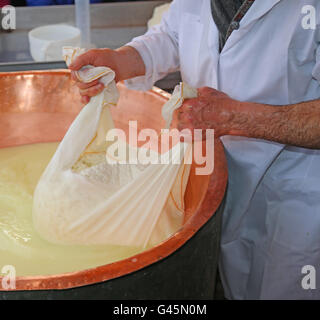 Senior expert fromager collecte le fromage avec la toile de la grande vasque en cuivre rempli de lait et lactosérum Banque D'Images