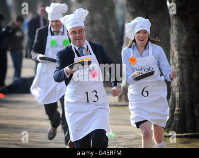 Le député travailliste Stephen Pound (à gauche), le député conservateur Tracey Crouch (à droite) et le rédacteur politique Channel four Gary Gibbon participent à la course parlementaire Pancake Race annuelle de Rehab UK à Westminster, Londres, pour aider à sensibiliser les gens aux problèmes de dicapacités. Banque D'Images