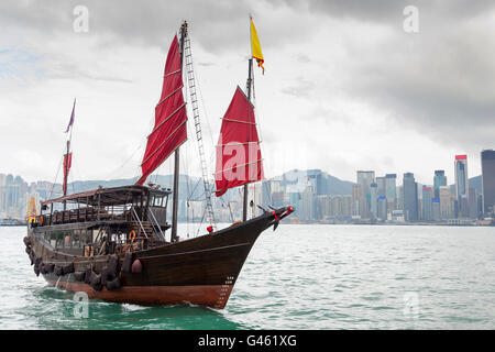 Une jonque chinoise avec navire voiles rouge sur le port de Victoria à Tsim Sha Tsui, Kowloon, Hong Kong's downtown quartier financier de Banque D'Images