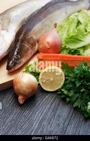 Paire de poissons crus river sur planche de bois près de légumes Banque D'Images