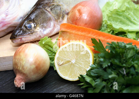 Paire de poissons crus river sur planche de bois près de légumes Banque D'Images