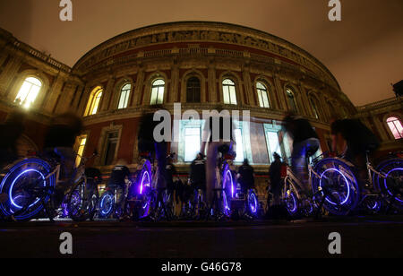 Une soixantaine de personnes produisent de l'énergie en pédalant sur des bicyclettes pour alimenter un projecteur et projeter un message pour l'heure de la Terre, organisé par l'organisme caritatif pour l'environnement WWF, à l'extérieur du Royal Albert Hall, à l'ouest de Londres. Banque D'Images