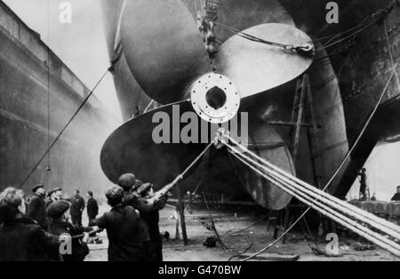 Une tâche délicate que les ouvriers tiennent soigneusement à la corde guide comme une nouvelle hélice de bronze de manganèse, 19 pieds 3 pouces de diamètre, est montée sur le dorsal Cunard RMS Mauretania, à Gladstone Dock, Liverpool. Banque D'Images
