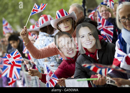 Les amateurs de Royal portent des masques de la reine Elizabeth II, du prince William et de Kate Middleton pendant qu'ils attendent le long de la voie processionnelle le jour du mariage royal. Banque D'Images