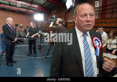 Jim Allister, le chef de TUV, parle lors d'une interview radio, comme Martin McGuinness (à gauche) de Sinn Fein le regarde, le deuxième jour du comptage à Ballymena, Co Antrim. Banque D'Images