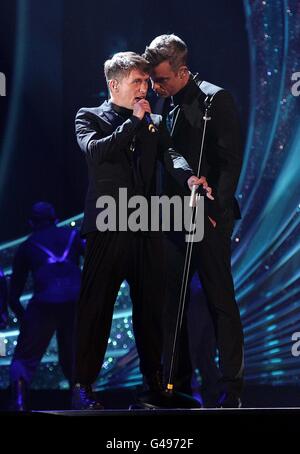 Robbie Williams (à droite) et Mark Owen of prennent cela lors des National Movie Awards 2011 à Wembley Arena, Londres Banque D'Images