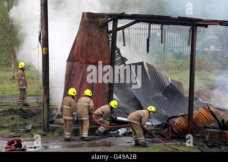 Des pompiers travaillent sur les lieux d'un incendie dans un hangar de chemin de fer à côté de la ligne ferroviaire principale d'Édimbourg à Glasgow à Bonnybridge, près de Cumbernauld. Banque D'Images