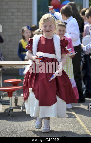 Erin McGowan, six ans, vêtue d'une princesse reçoit sa coupe en papier drapeau de l'Union et son assiette à l'école primaire Bucklebury de l'Angleterre fête de mariage royale dans le terrain de jeu de l'école. Banque D'Images