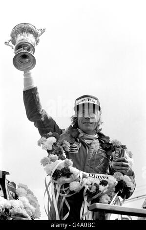 James Hunt de Grande-Bretagne avec le trophée des gagnants après avoir remporté le John Player Grand Prix britannique à Silverstone dans sa McLaren Banque D'Images