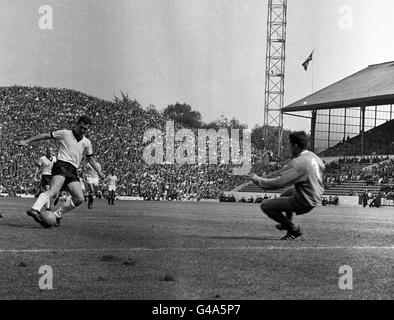 PA NEWS PHOTO : 23/7/66 : FRANZ BECKENBAUER D'ALLEMAGNE DE L'OUEST (À GAUCHE) DIRIGE LE BALLON AUTOUR DU GARDIEN DE BUT DE L'URUGUAY LADISLAO MAZURKIEVIEZ POUR MARQUER LE TROISIÈME BUT DE SON ÉQUIPE DANS LA FINALE DU QUART DE COUPE DU MONDE MATCHAT HILLSBOROUGH. L'ALLEMAGNE DE L'OUEST A GAGNÉ 4-0. Banque D'Images