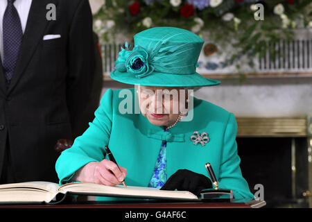 La reine Elizabeth II de Grande-Bretagne signe le livre des visiteurs à Aras an Uachtarain à Phoenix Park, Dublin. Banque D'Images