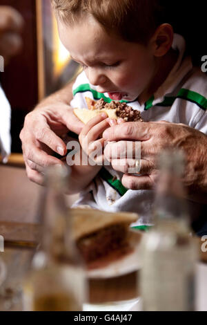 3 ans Emerson Bennett mange un hamburger avec des profils de l'aide à Louis' Lunch à New Haven, CT, USA, 26 mai 2009. Banque D'Images