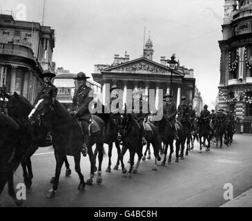 Les membres de la Gendarmerie royale du Canada, passent leurs chevaux à travers la ville de Londres, après la Bourse royale et la Banque d'Angleterre, à gauche, en route du Royal Albert Dock vers les lignes de chevaux à Hyde Park. Les quarante-six chevaux doivent être criés dans la procession du Couronnement. Banque D'Images