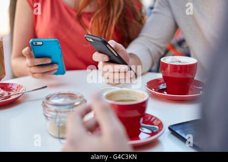 Parution du modèle. Les jeunes au cafe en utilisant les smartphones. Banque D'Images