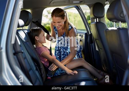 Parution du modèle. Mettre sur la fille mère de pari dans le siège arrière de la voiture. Banque D'Images