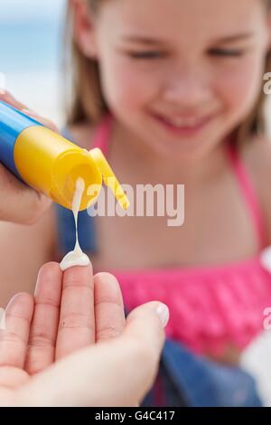 Parution du modèle. Personne appliquant la crème solaire à une fille, Close up. Banque D'Images