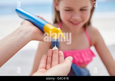 Parution du modèle. Personne appliquant la crème solaire à une fille, Close up. Banque D'Images