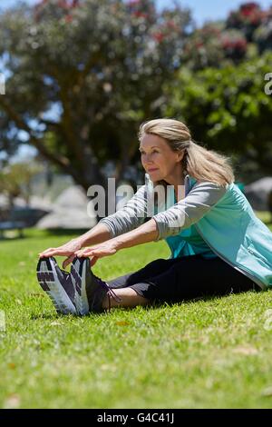 Parution du modèle. Senior woman stretching sur l'herbe. Banque D'Images