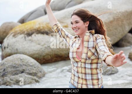 Parution du modèle. Jeune femme sur la plage avec les bras, en souriant. Banque D'Images