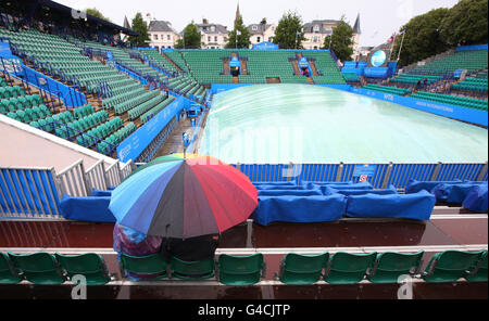 Les spectateurs se réfugient sous une bermella sur la cour centrale alors que la pluie retarde le jeu pendant l'AEGON International au parc Devonshire, à Eastbourne. Banque D'Images